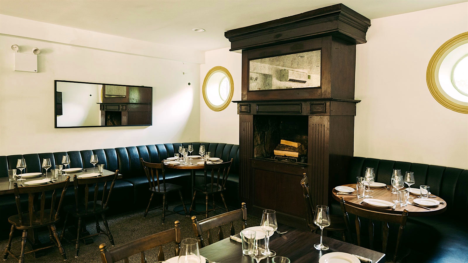     The dining room in Gus's chop house with dark banquettes, dark wood tables and fireplace cover